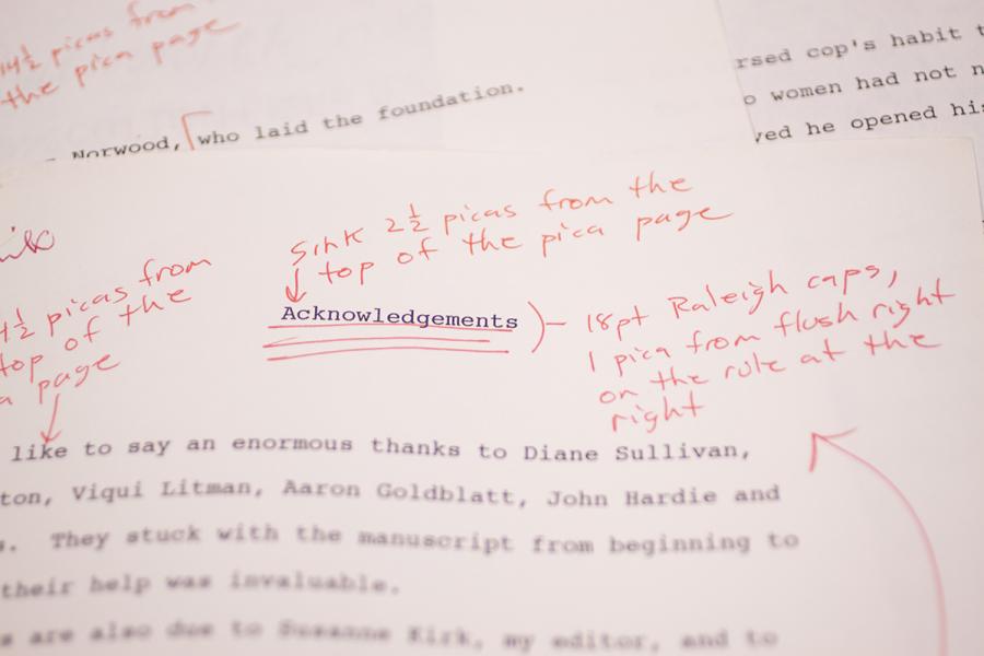 A close up of papers with black text and red writing on it. The sheet on top has the word Acknowledgements as the title.