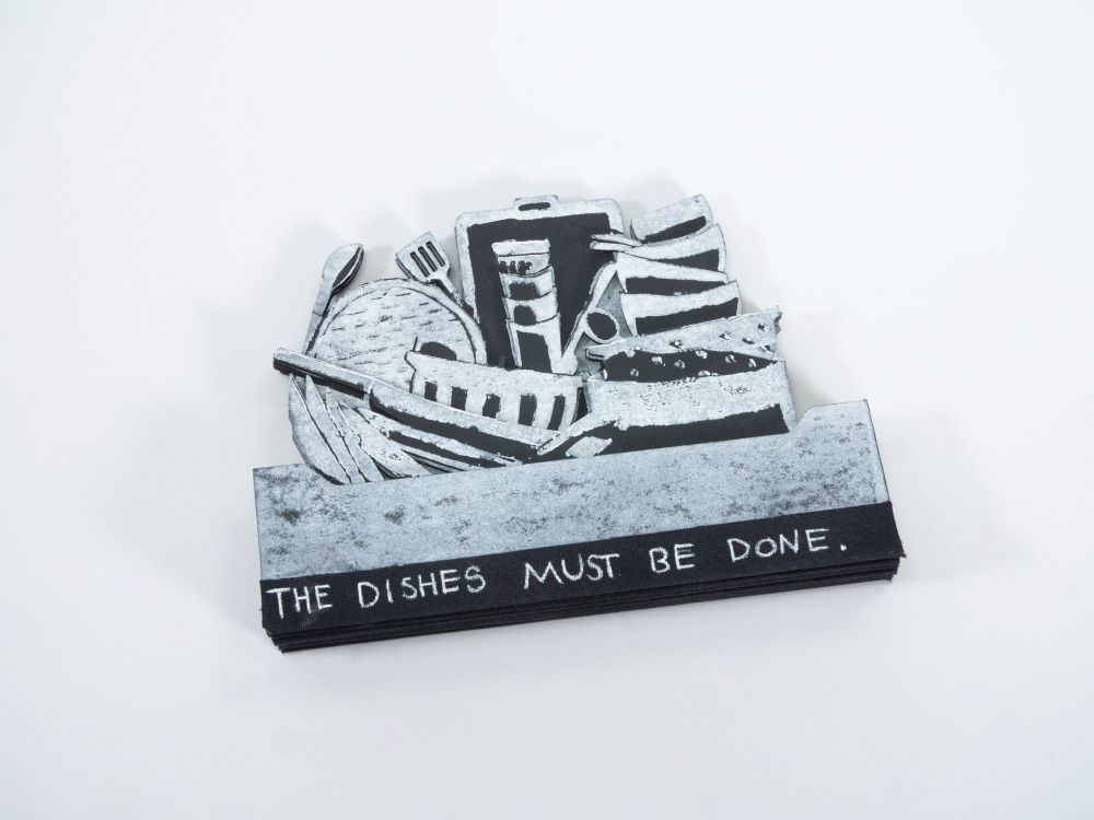 Layerd black boards layerd and cut into shapes like a stack of dishes, with printing in white. The boards are bound along the lower edge, and the title at the bottome reads The Dishes Must Be Done.