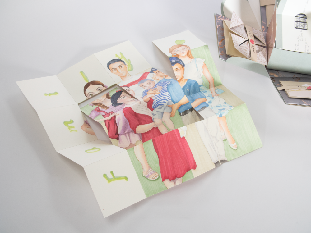 A sheet of paper that has been folded and cut into a sort of puzzle. The page has a hand drawn and colored image of a family standing together.