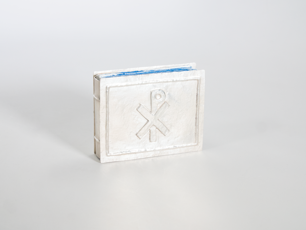 A small book with cover made of hammered silver, with a raised Chi Rho symbol.