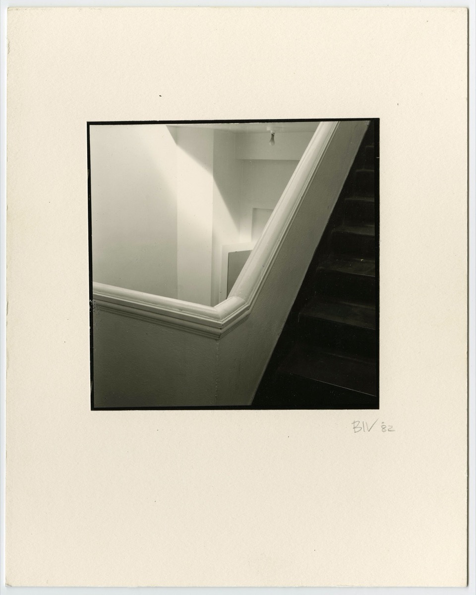 Black and white of a stairwell. The walls are white and the stairs are black.