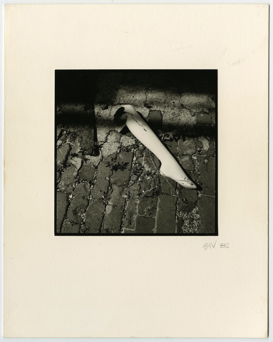 Foto en blanco y negro de una pierna de plástico sobre una pared de ladrillo.