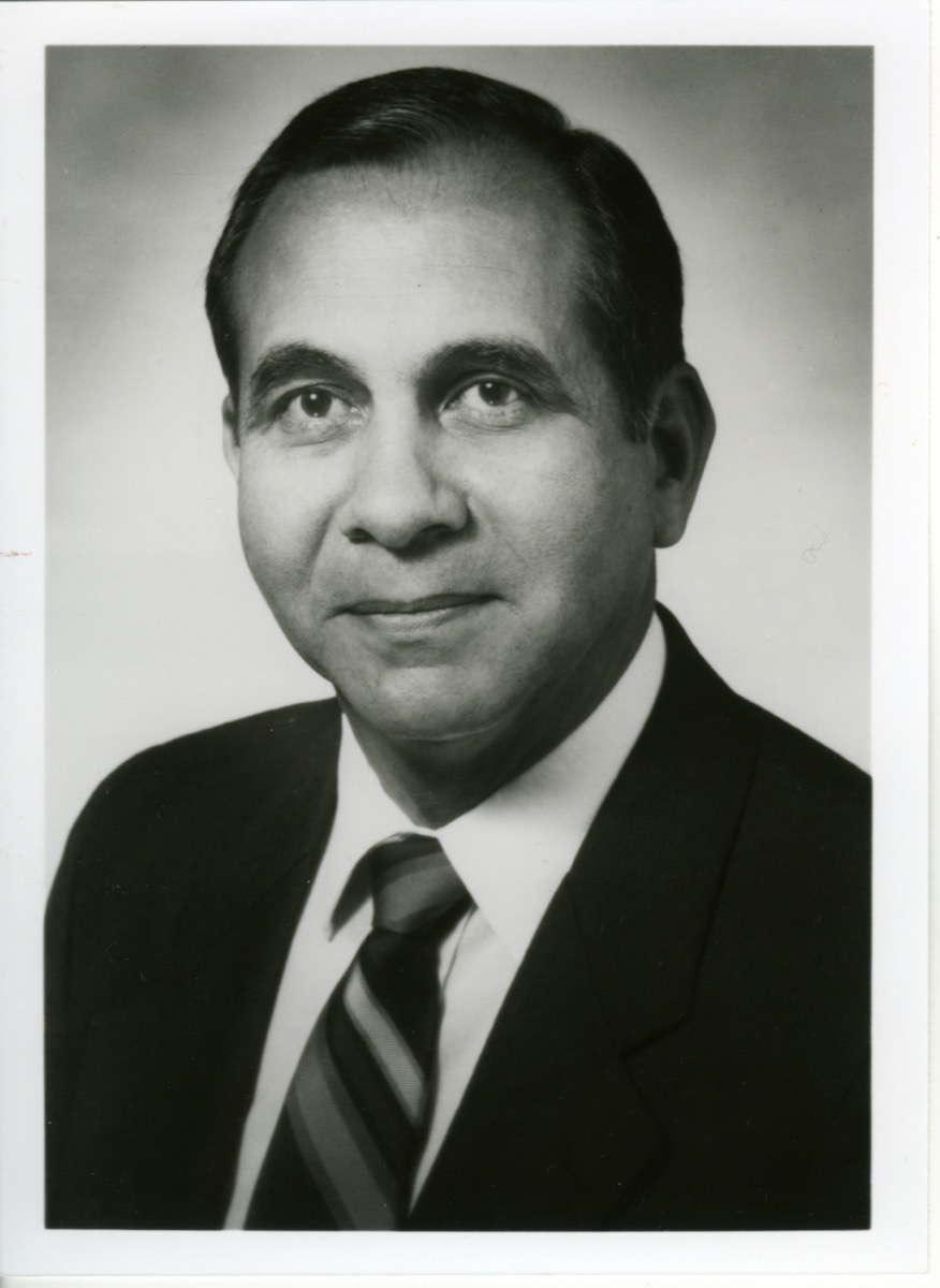 Un retrato de un hombre con traje negro y una corbata de rayas.